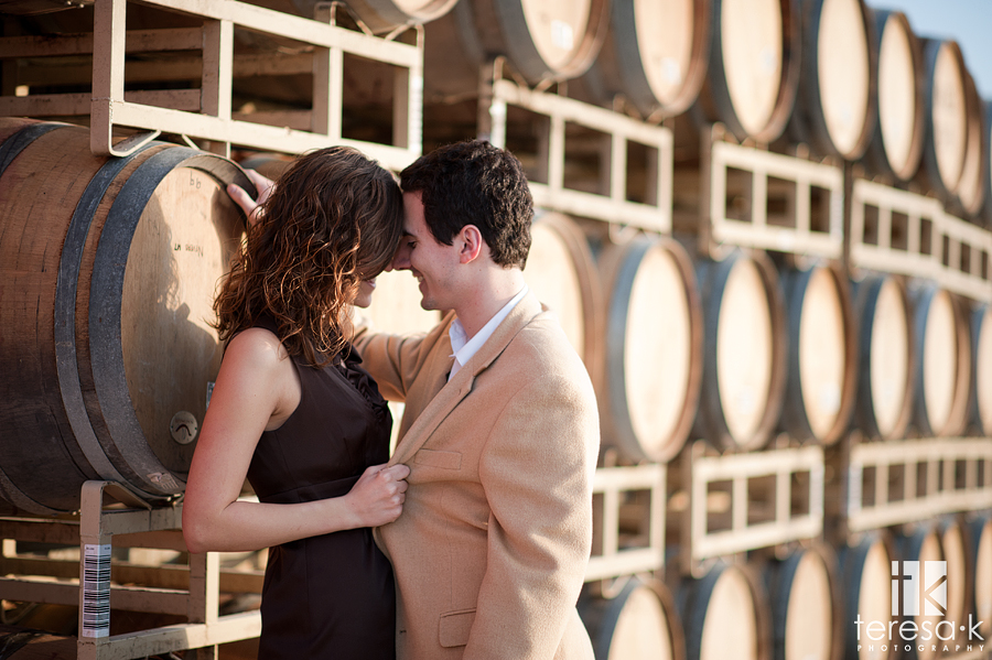 bride and groom kissing by wine barrels