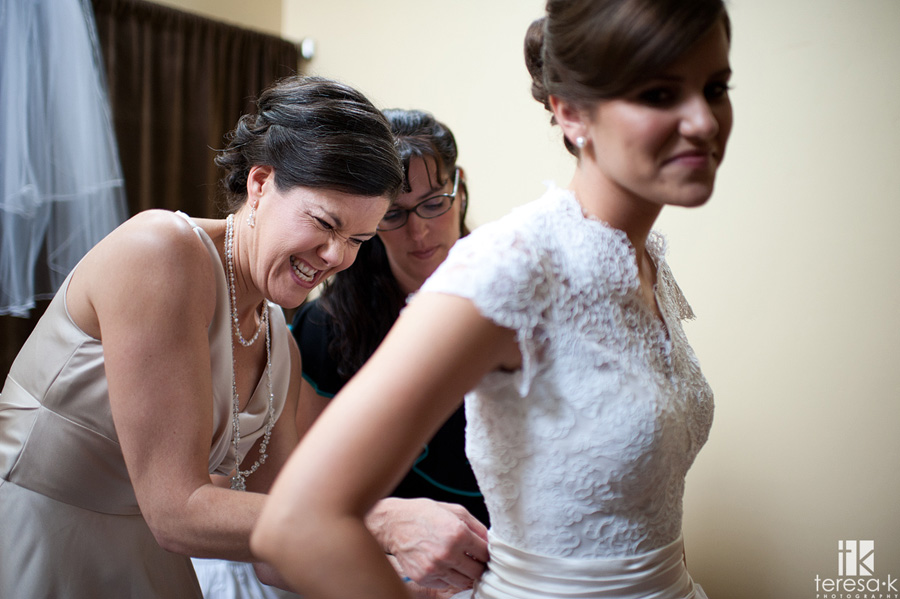 mother of bride having hard time buttoning the dress