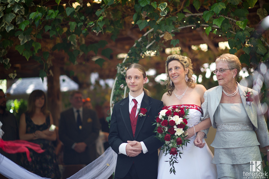 bride coming down aisle with mom and son