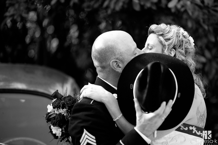 bride and groom kiss behind a hat