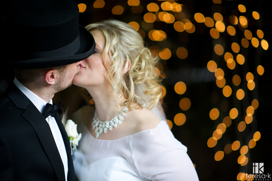 bride and groom kiss in front of lights